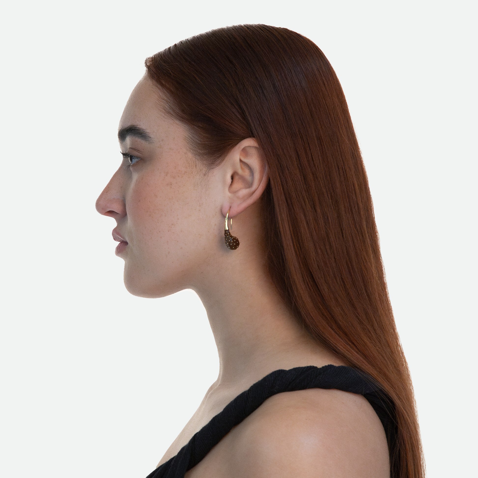 Side profile of model showcasing the unique design of Aspera earrings inspired by opuntia fruit with gold stem accents on a white background.