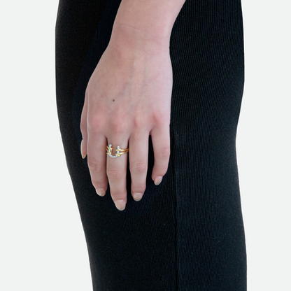 Side view of a model's hand wearing the Barbell Ring, showcasing the silver U-shaped piercing within the contrasting golden loop, designed by Ruggeri.