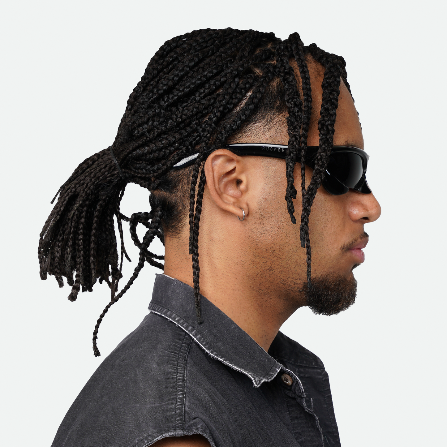 Side view of male model wearing Ruggeri Carapace sunglasses in all black, showcasing the sleek custom-moulded insectoid design with black lenses.