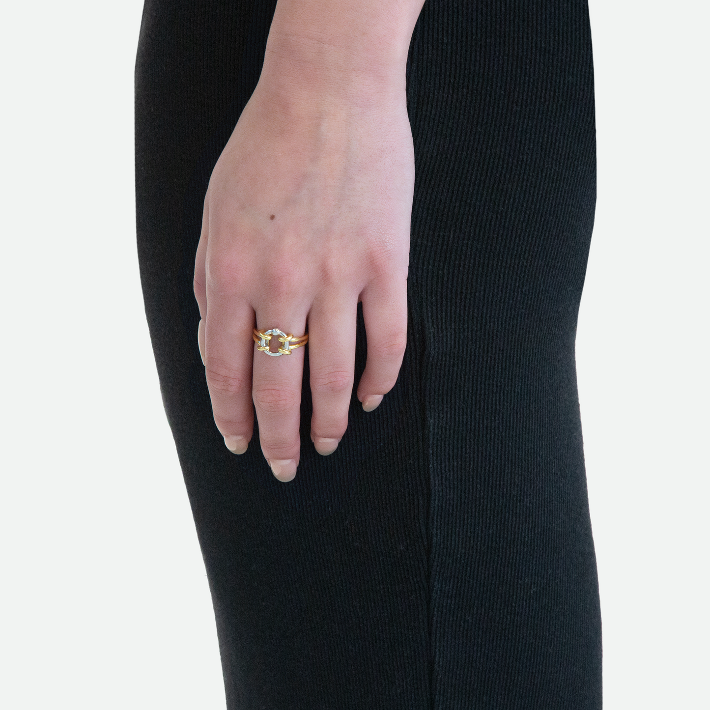 Side view of a model's hand wearing the Captive Ring, showcasing the silver O-shaped piercing encased within the contrasting golden loop, designed by Ruggeri.