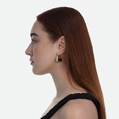 Side profile of model wearing the Pouch earring, highlighting the gold plated brass and subtle Ruggeri logo engraving, on a white background.