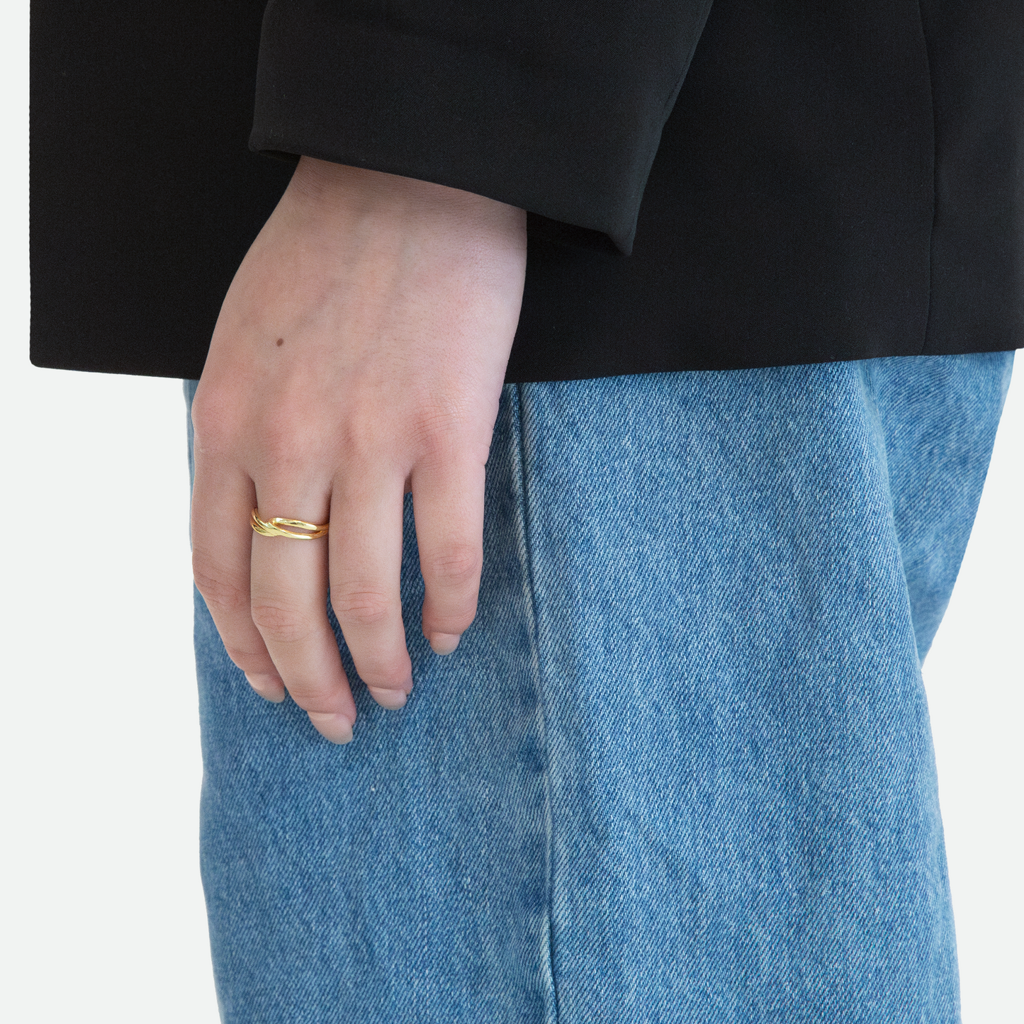 Side view of a model's hand wearing the Implico ring, highlighting the intertwined forms in polished gold that touch at the center, designed by Ruggeri.