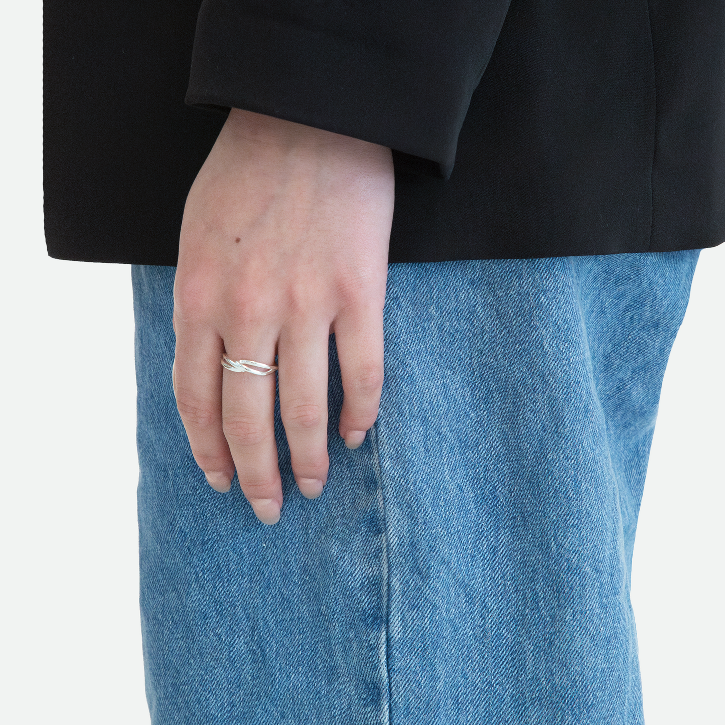 Side view of a model's hand wearing the Implico ring in silver, emphasizing the intertwined forms that touch at the center, designed by Ruggeri.