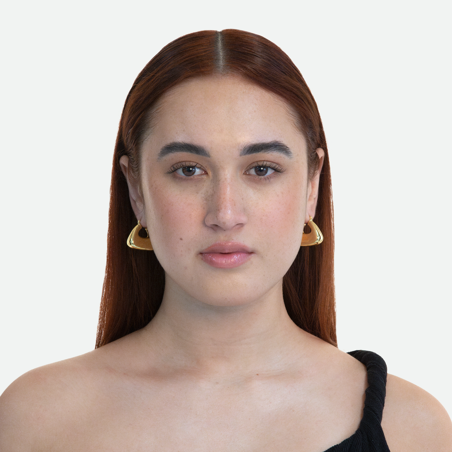 Model showcasing the simple and versatile Pouch earring with a gold inflated hoop design engraved with the Ruggeri logo, on a white background.