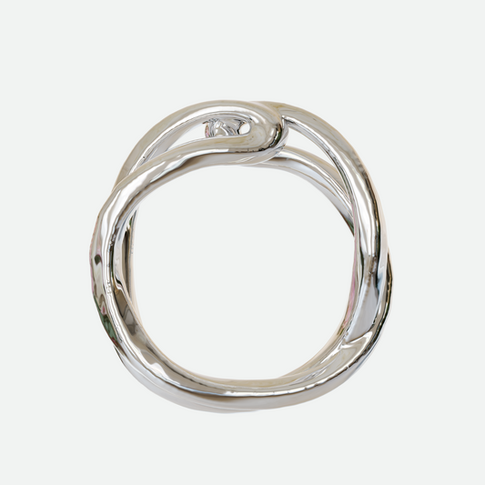 Implico ring in polished silver, where two forms intertwine and touch at the center, showcasing an interplay of shapes, designed by Ruggeri.