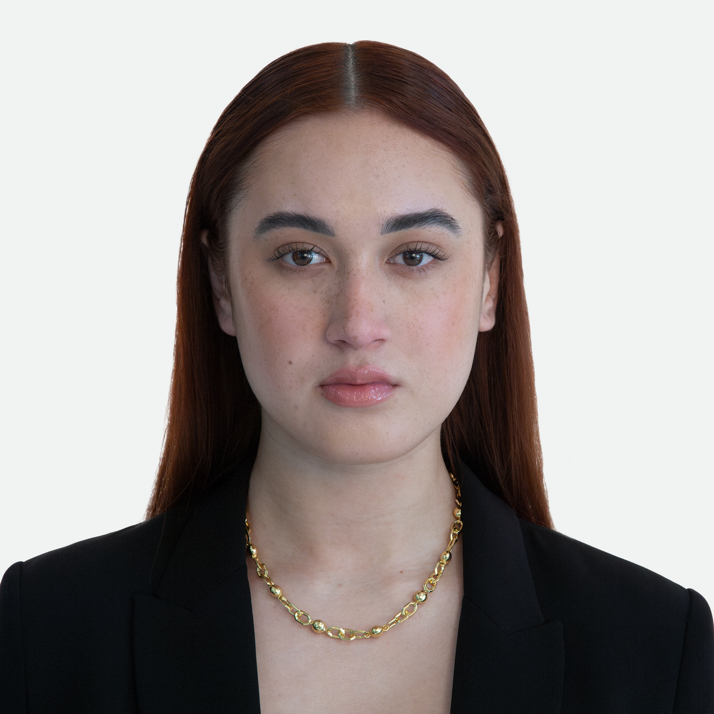 Model wearing the contemporary Sphera necklace, showcasing its distinctive hexagonal links and gold pearls, on a white background.