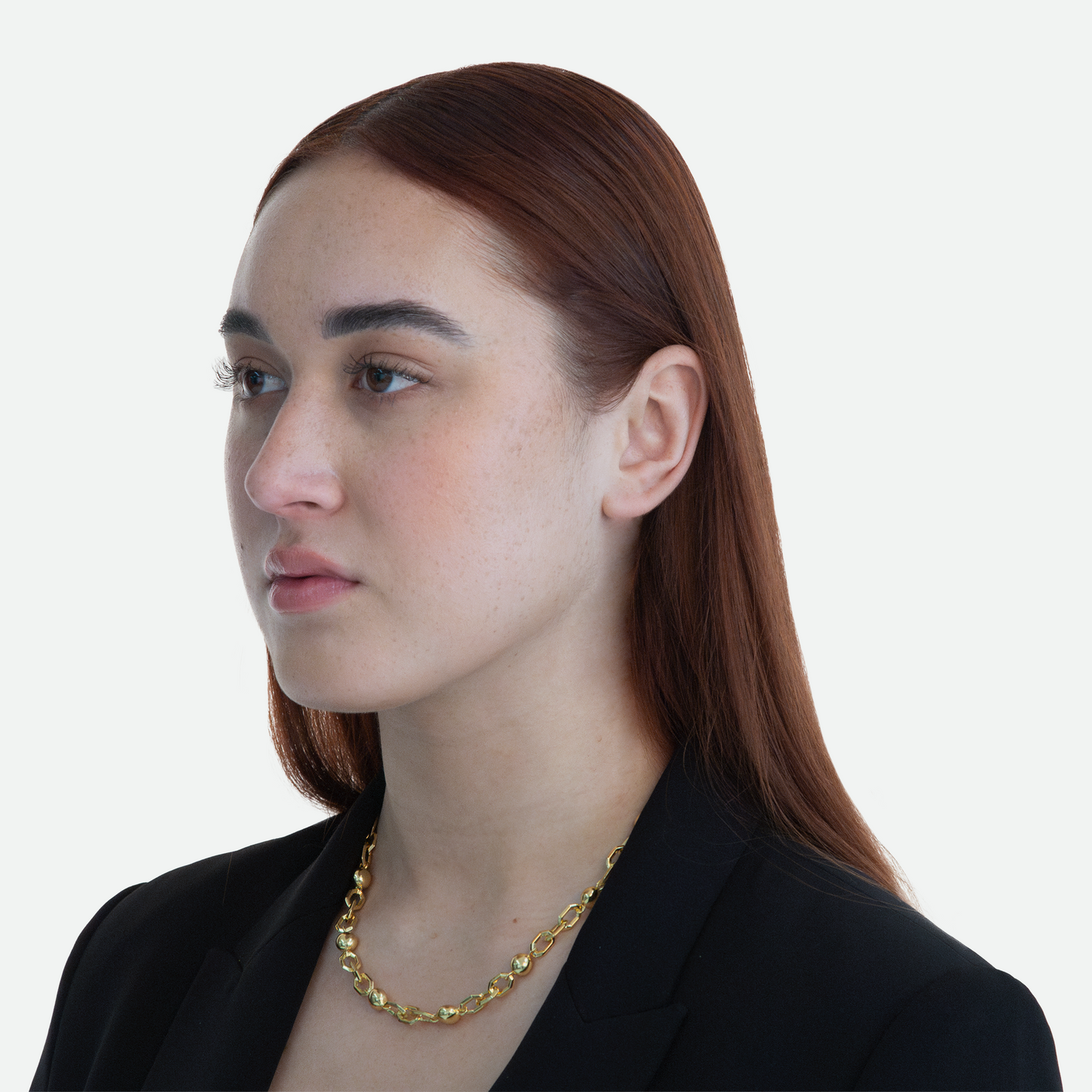 Model at a 45-degree angle view wearing the Sphera necklace, highlighting the striking contrast of hexagonal links and smooth pearls of gold, on a white background.