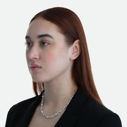 Model at a 45-degree angle view showcasing the Sphera necklace, emphasizing the unique interplay between its custom hexagonal links and silver pearls, on a white background.