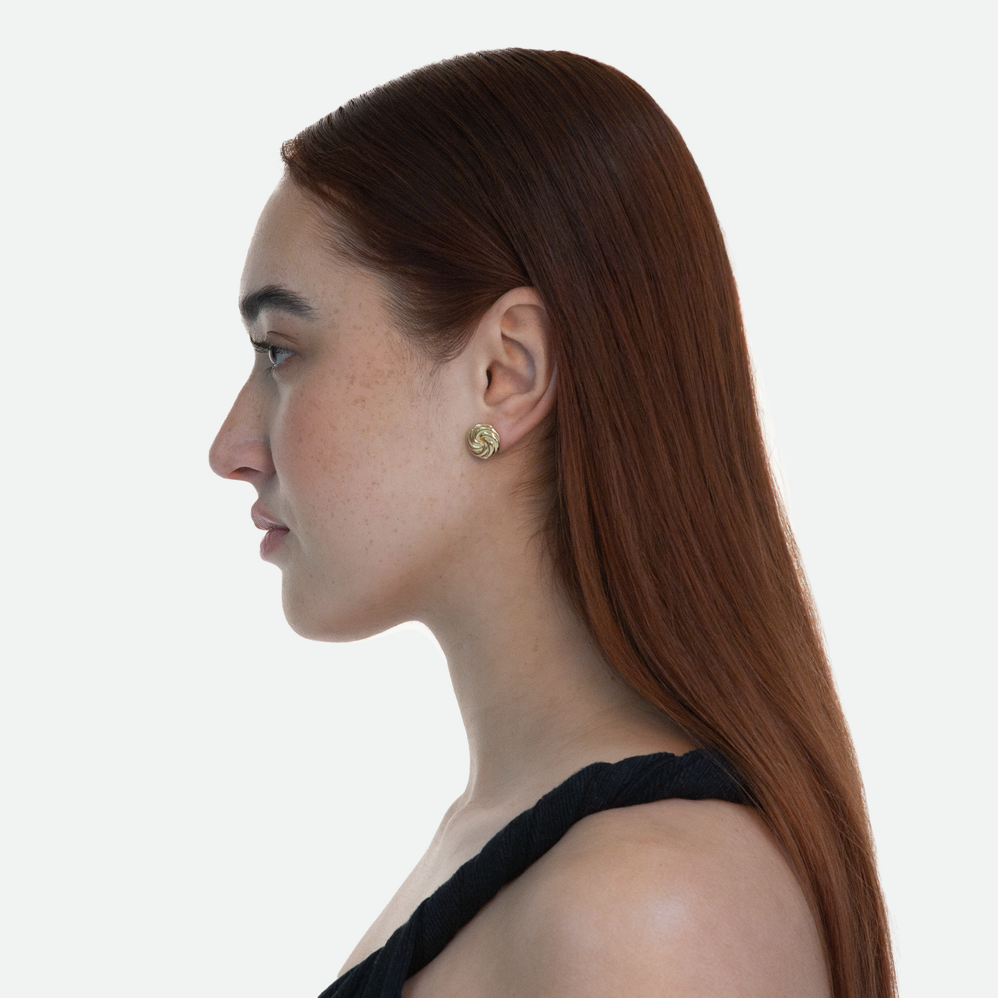 Side profile of model wearing the Gold Vortex earring, highlighting the understated design of twin gold whorls, on a white background.