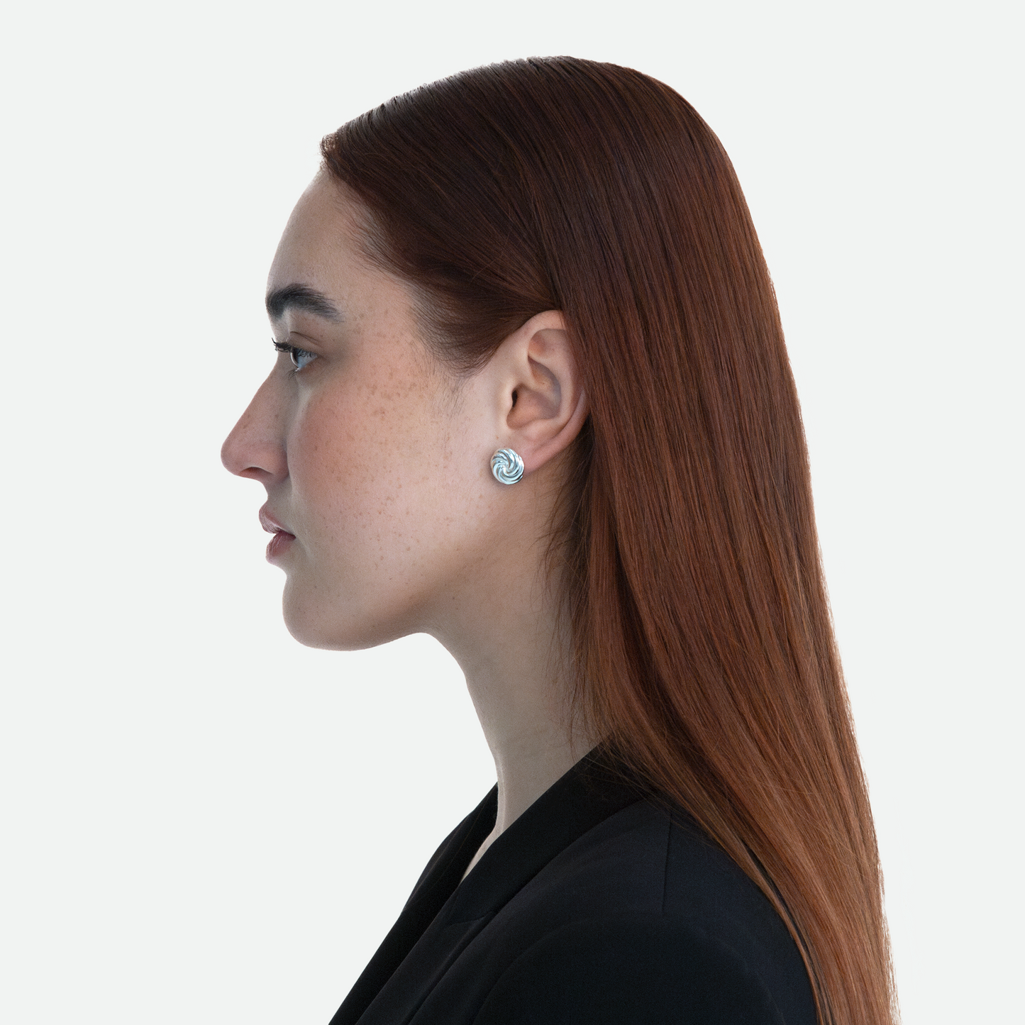 Side profile of model wearing the Silver Vortex earring, highlighting the understated design of twin silver whorls, on a white background.